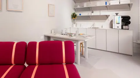 Museum of the Home The exhibition's Innovo Room of the Future, a white room with white kitchen units, a white table and a bright red sofa