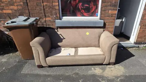 Jessica Stratton/LDRS Old sofa outside terraced house with yellow sticker