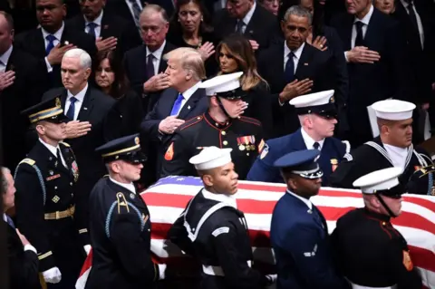 Getty Images George HW Bush's casket is carried past Mike Pence, Donald Trump, Melania Trump and Barack Obama as they each hold their right hand to their chest as a sign of respect.