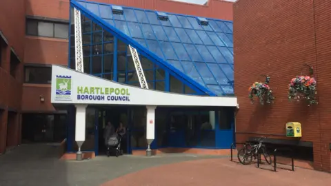 Hartlepool Borough Council building. A bike is locked up outside a glass reception area.
