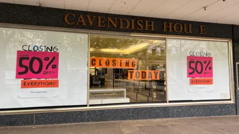 A photo of a shop front with a Cavendish House sign above a window. In the window are closing down signs.