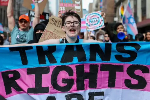Trans activists march in New York City bearing banners