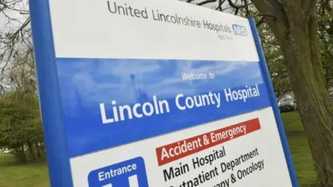 Close-up photo of Lincoln County Hospital blue and white sign in front of grass verge.