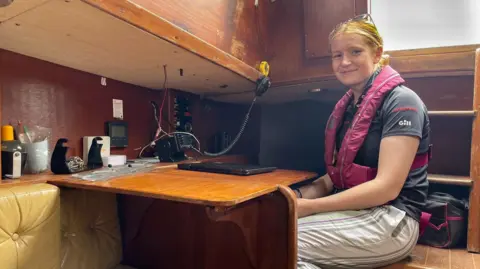 A young woman is sat by her radio inside the boat