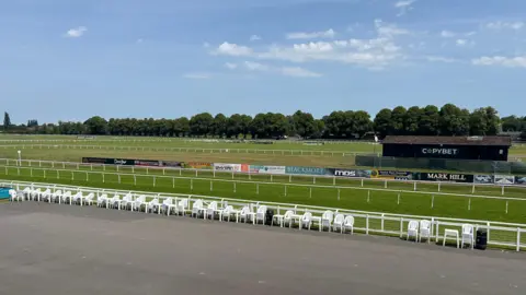 The view of Worcester racecource, featuring chairs and railings in the background.