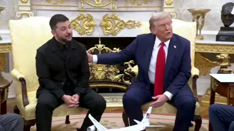 Donald Trump, seated next to Volodymyr Zelensky in the Oval Office