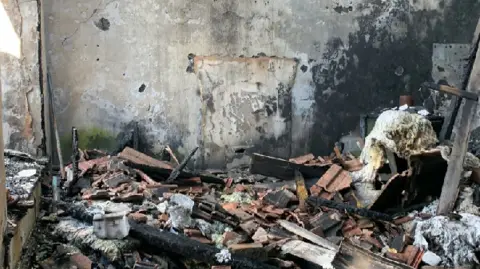 Paul Fosh Auctions The inside of a building damaged by a fire, with burnt rubble and debris on the ground