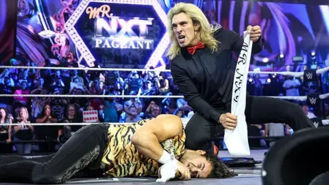 Getty A wrestler celebrates victory beside his defeated opponent 