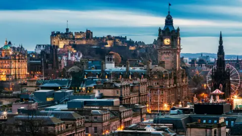 Getty Images An image of the city centre of Edinburgh in twighlight, with lights illuminating landmarks on the skyline including the Scotsman hotel building and the Scott Monument on Princes Street, and Edinburgh Castle in the background