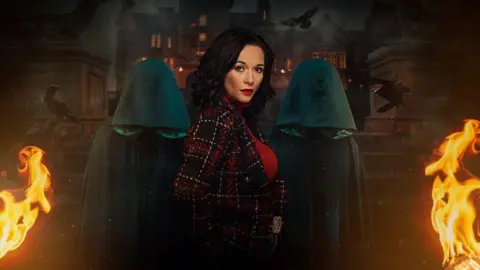 BBC Charlotte Chilton is depicted in a promotional image for The Traitors. She is gazing at the camera from the side, with two individuals in green hoods behind her. They are all positioned in front of the steps of a castle, with flames on both sides.