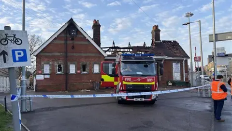 Luke Deal/BBC The outside of a charred station building, with a fire engine parked up in front. There is police tape across the driveway to the building. A road crossing can be seen to the right, along with people in hi-vis jackets.