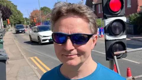 Nick Marsh, wearing sunglasses, standing on Main Road in Sutton-at-Hone