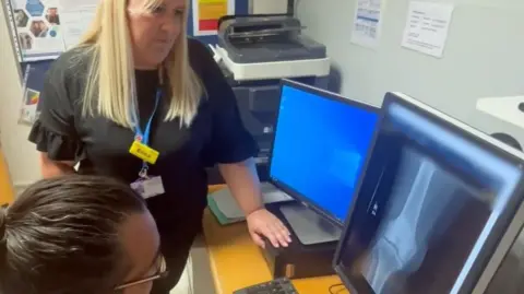 Two NHS staff look at an X-ray scan on a computer screen