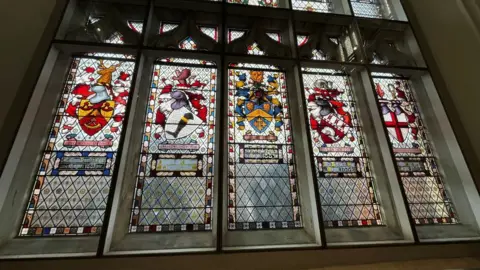Shaun Whitmore/BBC A stained glass window which has five panels.