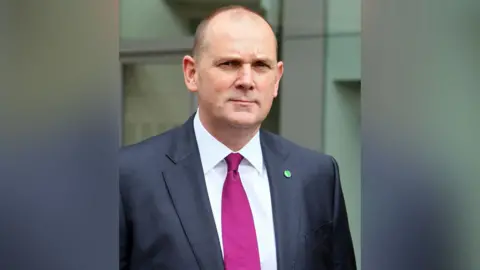 PA Media A man with a pink tie and a grey suit 