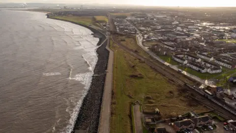 Brownfield sites at Hartlepool waterfront, viewed from the air, with the muddy brown-grey sea visible on the left.
