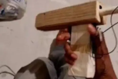 Met Police A blurry mobile phone image of a young man's hand holding what looks like a gun crudely fashioned from bits of wood and tape.