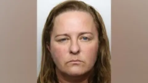 A mugshot of an unsmiling Stacey Smith, a 46-year-old with brown hair and blue eyes