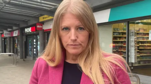 Donna jones wearing black and pink and stood in the high street