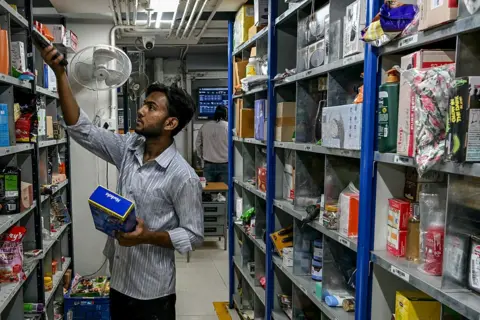 Bloomberg via Getty Images In this photograph taken on March 21, 2025, a worker scans items while preparing a customer's order for delivery at a BigBasket dark store, in Mumbai