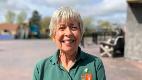 A woman in a green Visit devon T shirt is outside at Crealy Theme Park and Resort in Devon. 