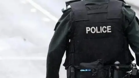 A police officer wearing a bulletproof vest with 'police' written on the back.