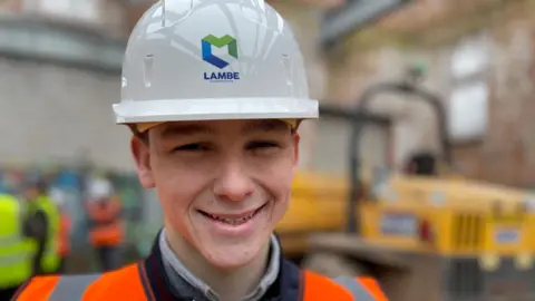 Young man in a white hard hat and orange hi-vis vest