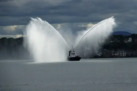 George Stewart A tugboat with two jets of water being propelled from its sides
