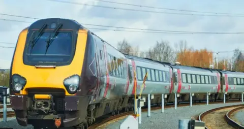 An inter-city train on tracks on a grey day.