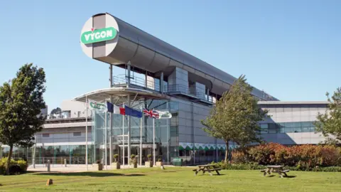 Vygon UK A futuristic looking glass-paneled building with flags in the foreground which is the former Motorola building (now Vygon UK).