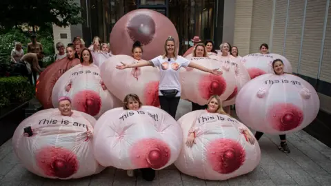 A group of women dressed as inflateable breasts stood outside of Meta HQ in London
