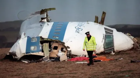 Getty Images Los restos de Pan Am Flight 103, rechazado el 21 de diciembre de 1988. Un oficial de policía se encuentra frente al avión destrozado.