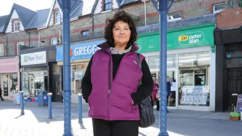 Getty Images Caroline Jones, a woman with brown curly hair and wearing a purple jacket, stands in a high street
