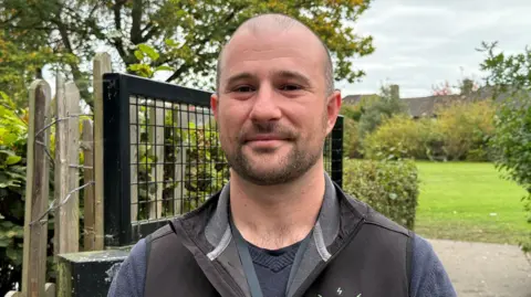Cameron Noble/BBC Aaron Rushworth smiling outside school gates. 