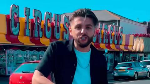 Leon Mallett in his music video standing in front of amusements on Great Yarmouth seafront