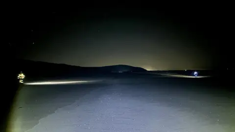 Millom Coastguard Rescue Team Search lights on the beach at night with two of the rescue team scouring the area