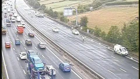 Traffic camera image showing slow-moving traffic on the northbound carriageway, and a police scene in place on the northbound route