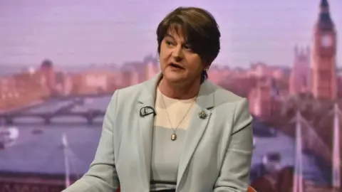 Arlene Foster, a woman with dark hair, wearing a grey suit.