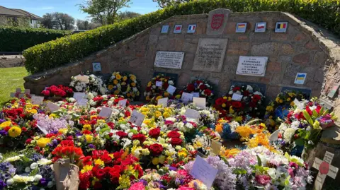 Wreaths of flowers are laid out on the ground with many containing special messages from families and loved ones