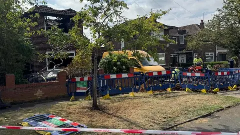 A red and white tape cordons of the scene at the fire damaged house
