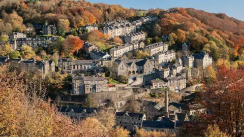 A picture of houses built in a valley surrounded by trees