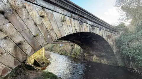 NYMR A close up of an old stone bridge with a river underneath it 