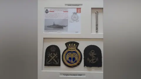 Raymond McCullough A white frame with badges and a piece of paper detailing the Yangtze incident.