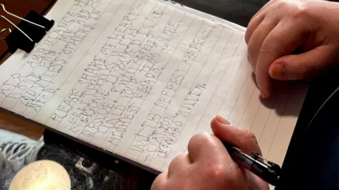 A pair of hands holding down a piece of paper on a clipboard - the words are spidery but they can be read and it says "Air Ambulance...done for me and for countless others in need. Please share my heartfelt thanks with everyone involved in my recue. I will forever hold your team in the highest regard. With deepest appreciation, Leonard Mullin