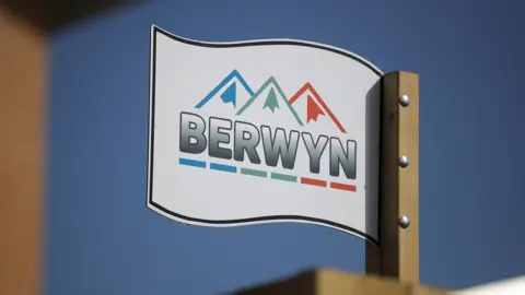 Getty Images A general view of a white sign at HMP Berwyn with the name on it, with an illustration of three mountain peaks in blue, green and red. There is a blue sky behind.