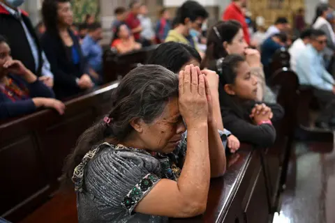 AFP People pray during a mass for the health of Pope Francis at the Metropolitan Cathedral in Guatemala City on 23 February 2025.