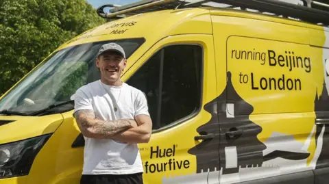 Jack Jarvis stood with his arms folded in front of his yellow and black "running Beijing to London" van.