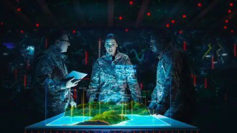 University of Lincoln Three people, a woman and two men, all dressed in Army fatigues, stand around a table. The table is showing a computer simulated landscape.