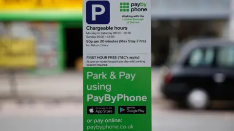One hour free parking sign with plenty of details of timing and how to pay. The sign is mostly white and green.