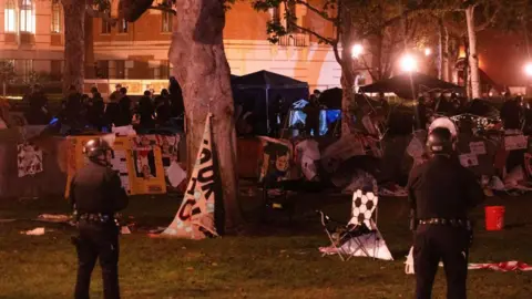 Getty Images Two police officers stand in front of a pro-Palestine encampment at USC